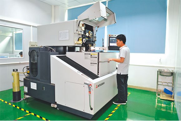 Wire EDM machine cutting a part, operator at the control